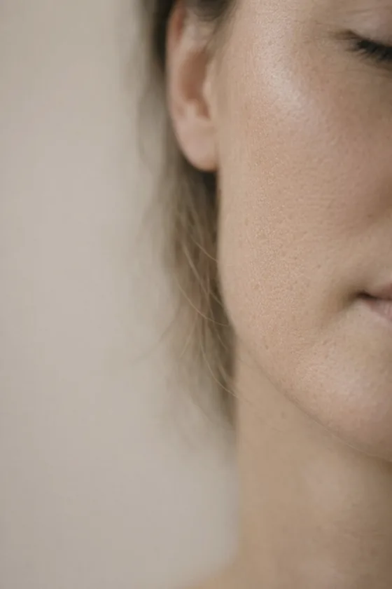 Editorial photograph: close up of clear skin along a cheek and jaw, lit from the side